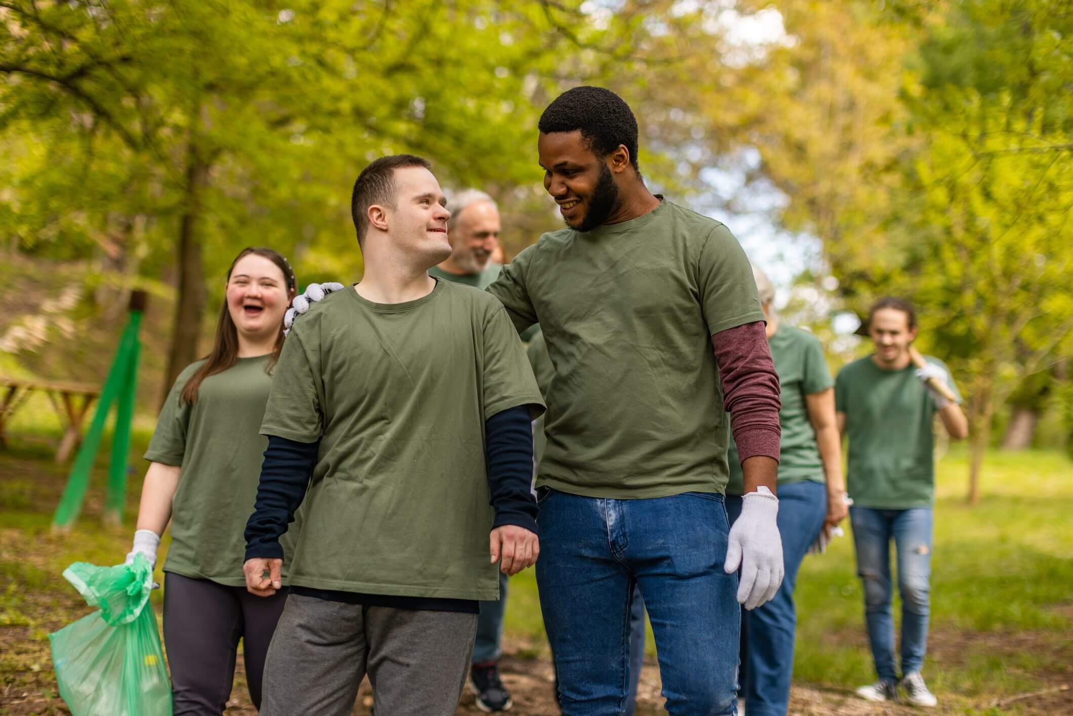 Two men, one with Down syndrome, share a joyful moment outdoors during a group walk.