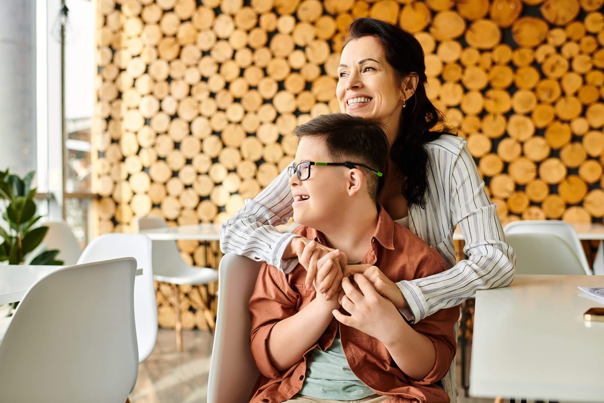 Mother and son sharing a joyful moment indoors with a wooden log backdrop.