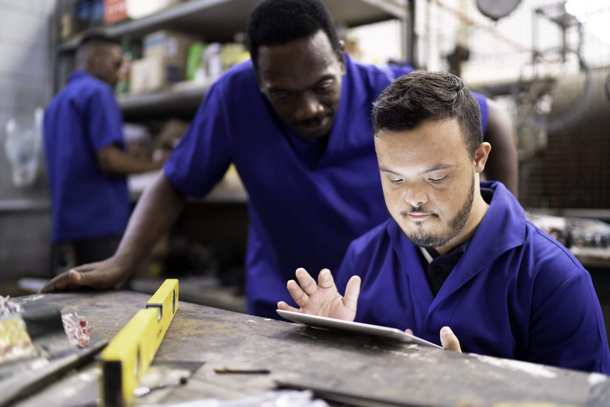 Two men in blue uniforms working together on a project.