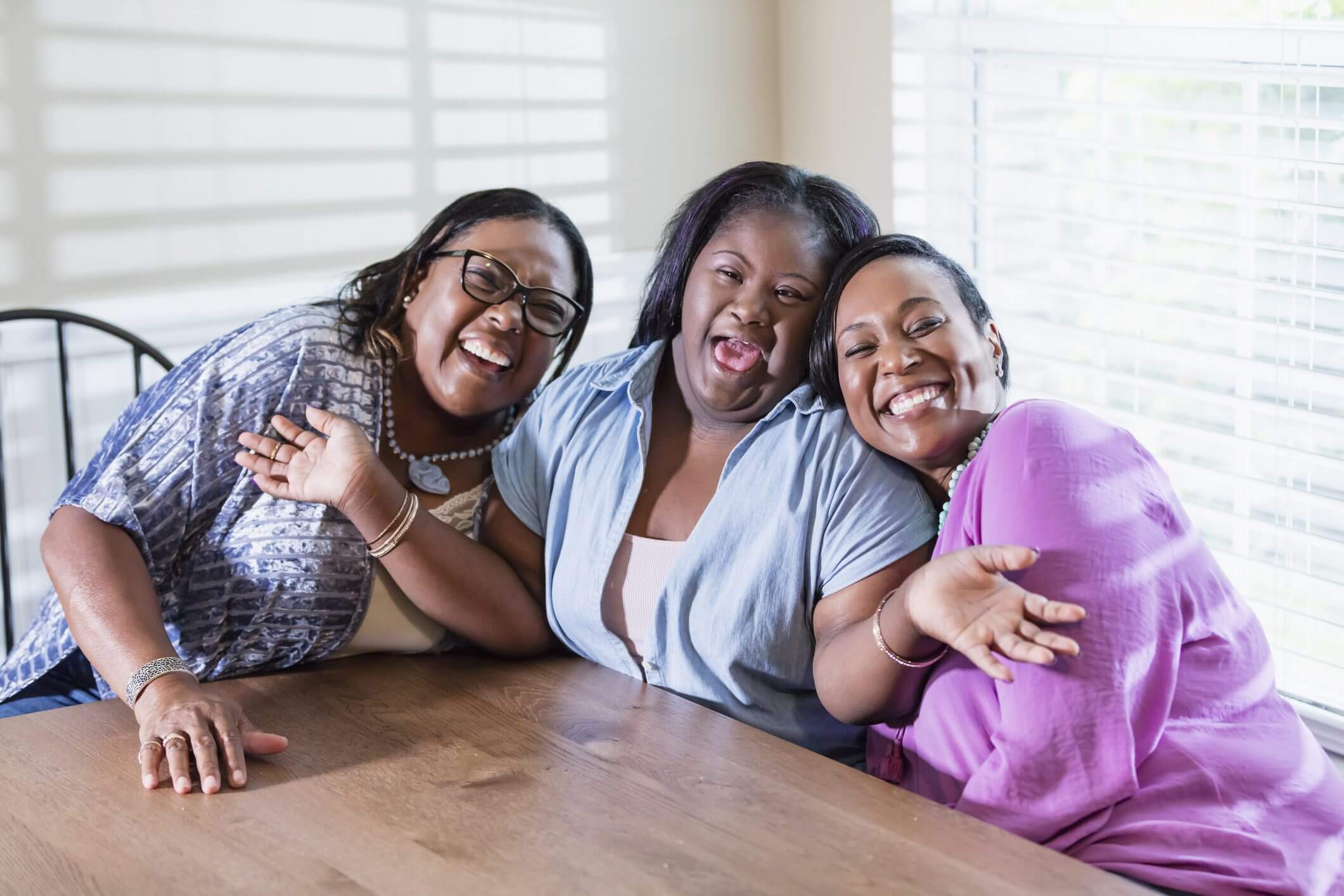 Three women smiling and enjoying time together at a table.