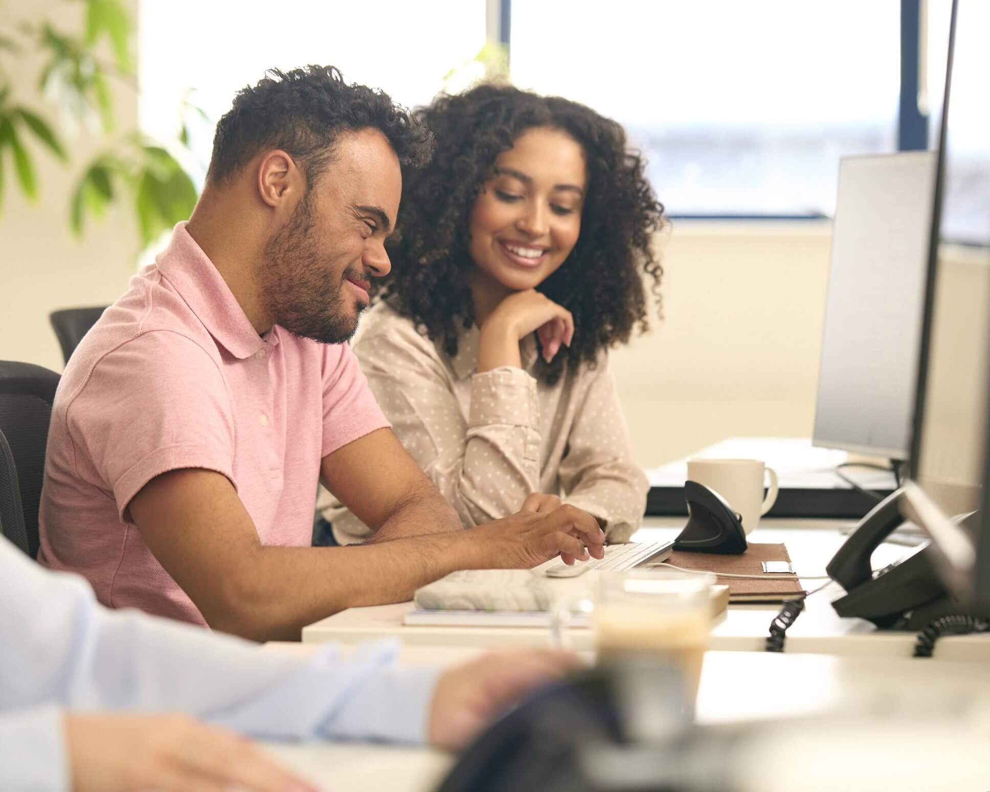 Smiling colleagues collaborating at office desk.