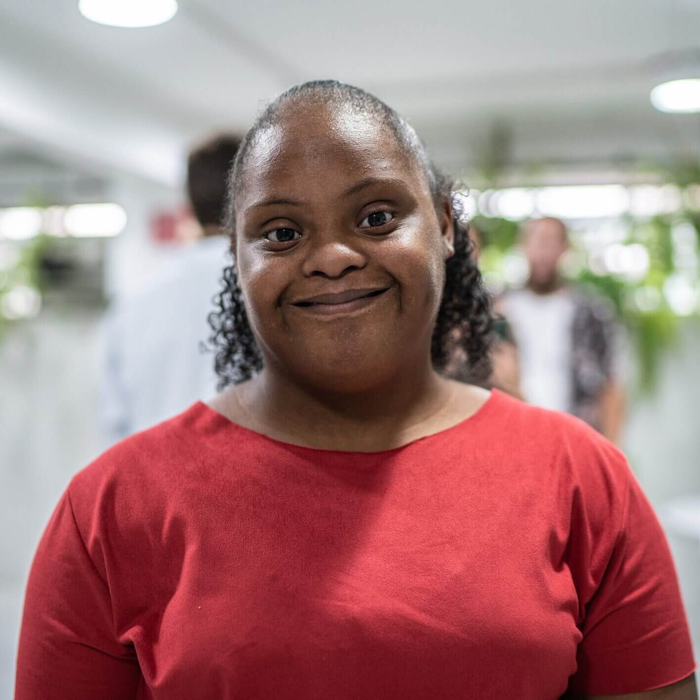 Smiling woman in a red shirt indoors.